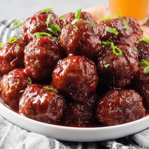 The Best Cranberry Meatballs 2 A white bowl filled with glossy cranberry meatballs garnished with fresh green onions.