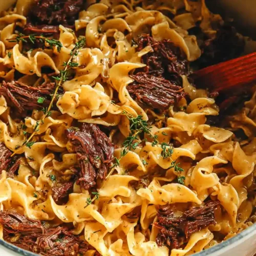 The BEST Beef and Noodles 3 Tender beef and noodles in a creamy savory sauce with shredded beef mixed into egg noodles, served in a large pot.