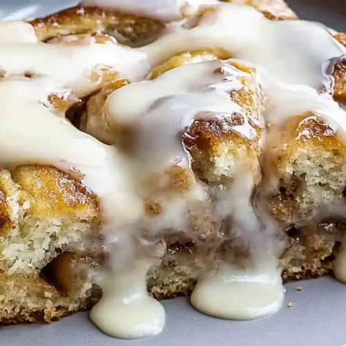 Cinnamon Roll Cake 2 Slice of cinnamon roll cake topped with creamy icing dripping down the sides.