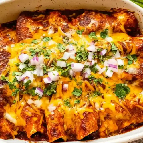 Easy Beef Enchiladas Recipe 2 Cheesy beef enchiladas baked in red sauce and topped with cilantro and diced onions.