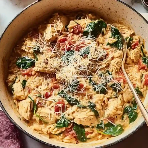 The Best One-Pan Chicken Orzo Recipe 2 Overhead view of a creamy chicken orzo pasta dish with spinach, tomatoes, and Parmesan in a skillet, ready to serve as a comforting meal.