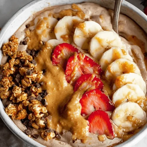 Fluffy Protein Yogurt Bowl Recipe 2 Vibrant Fluffy Protein Yogurt Bowl overhead, topped with granola, chocolate, nut butter, strawberries, and bananas on marble.