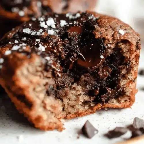 Healthy Banana Protein Muffins 2 Close-up of a partially eaten golden-brown Banana Protein Muffins with molten chocolate and sea salt flakes.