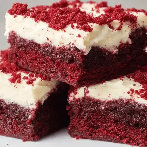 Fudgy Red Velvet Brownies with Cream Cheese Frosting 2 Three slices of decadent Red Velvet Brownies with cream cheese frosting and crumb topping on a white plate.