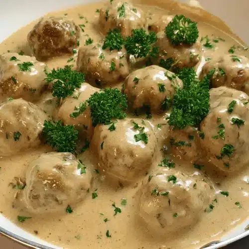 Classic Swedish Meatballs Recipe 2 A pan of creamy, parsley-garnished Swedish meatballs Recipe.