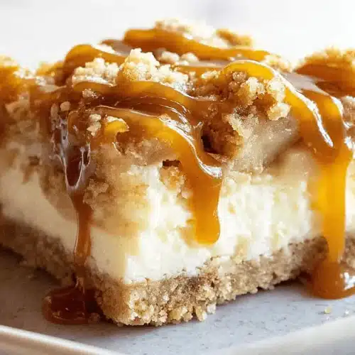 A single delicious slice of Caramel Apple Cheesecake Bars with a crumble topping and rich caramel drizzle on a gray plate.