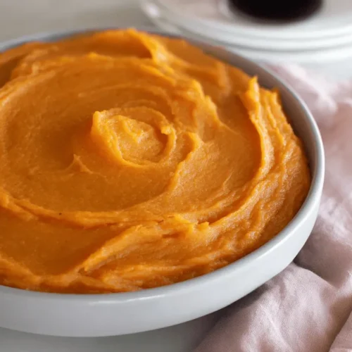 A beautifully swirled, creamy sweet potato pudding in a ceramic bowl, ready for a comforting meal.