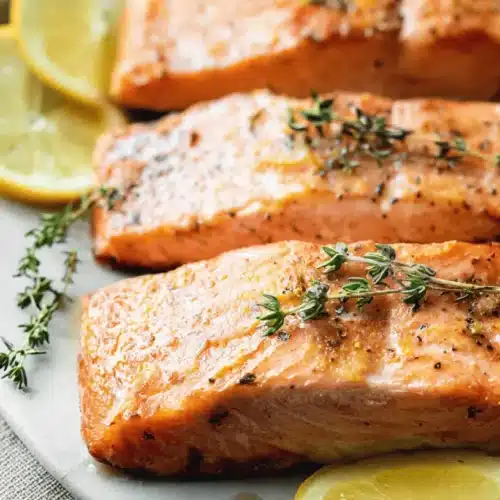 Close-up of perfectly cooked baked salmon fillets with lemon and herbs, showcasing a delicious baked salmon recipe.