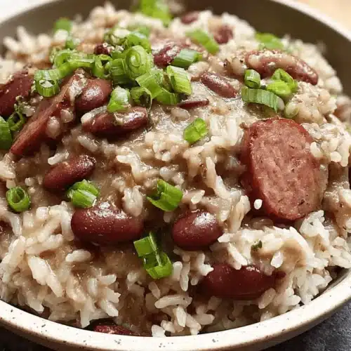 Hearty bowl of red beans and rice with sausage, garnished with green onions, showcasing a classic red beans and rice recipe.
